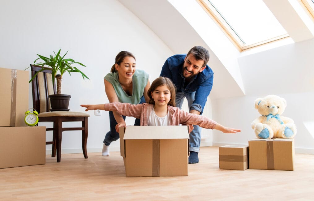 Happy family with young children moving into a new home with cardboard boxes
