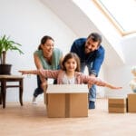 Happy family with young children moving into a new home with cardboard boxes