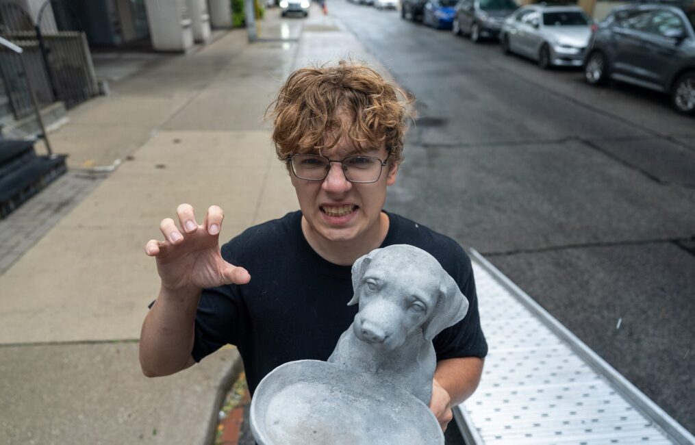 Moving Co. mover clowning around while carrying a stone dog statue