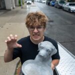 Moving Co. mover clowning around while carrying a stone dog statue