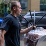 Moving Co. mover carrying a plastic-wrapped chair to the truck