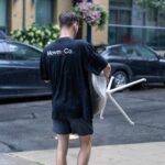Moving Co. mover carrying a wrapped item along a city sidewalk