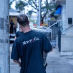 Moving Co. mover with the logo on his shirt carrying a wrapped item down the sidewalk