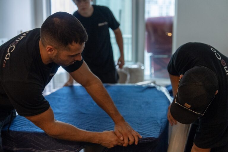 Moving Co. movers covering a table with moving blankets