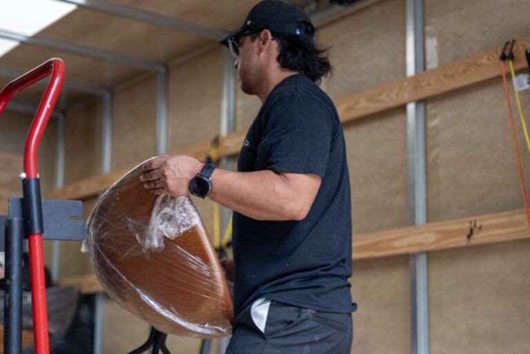 Moving Co. mover lifting a wrapped chair inside the truck