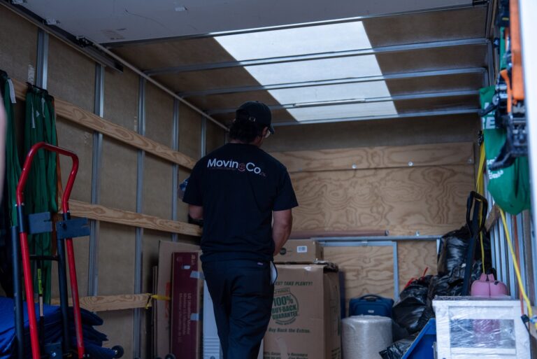 Moving Co. mover loading boxes into the back of the moving truck