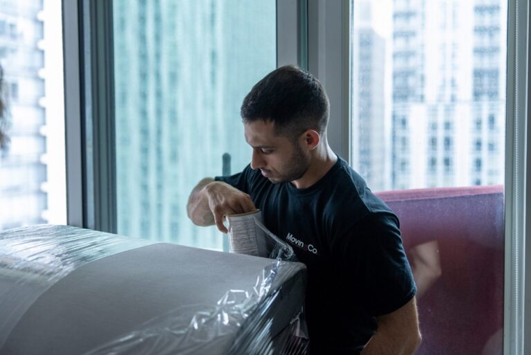Moving Co. mover shrink-wrapping a sofa in a condo before the move