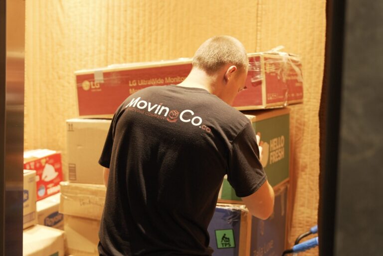 Moving Co. mover stacking boxes in a padded service elevator