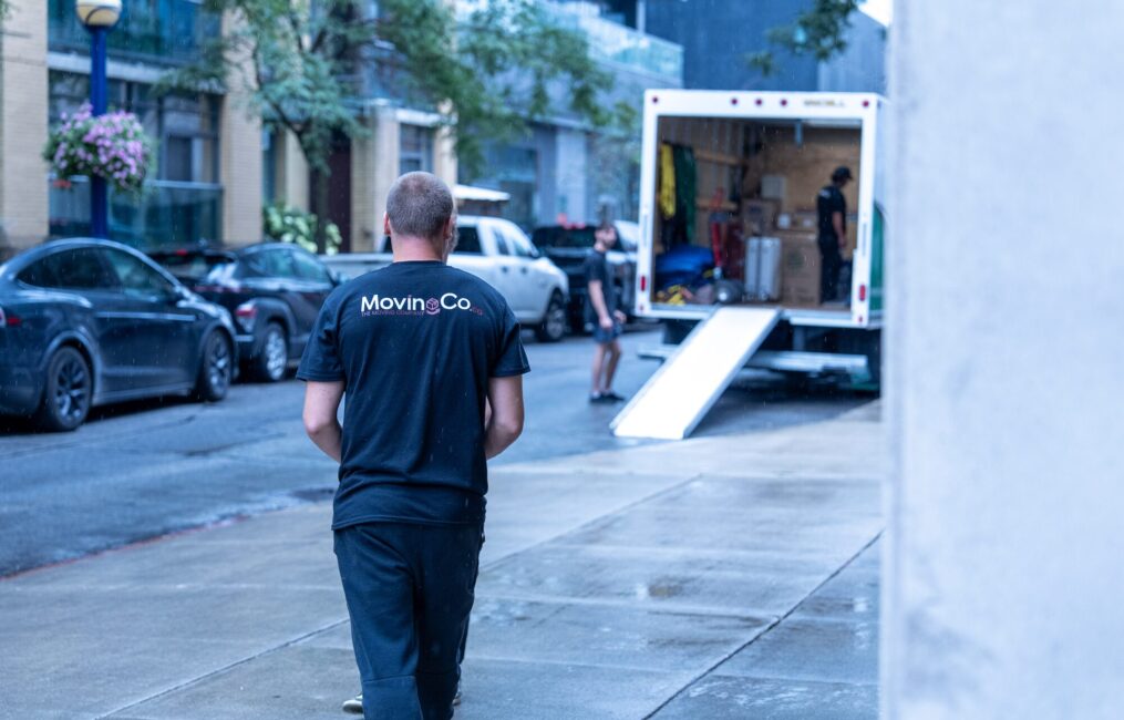 Moving Co. mover walking along the street to the truck with its ramp down