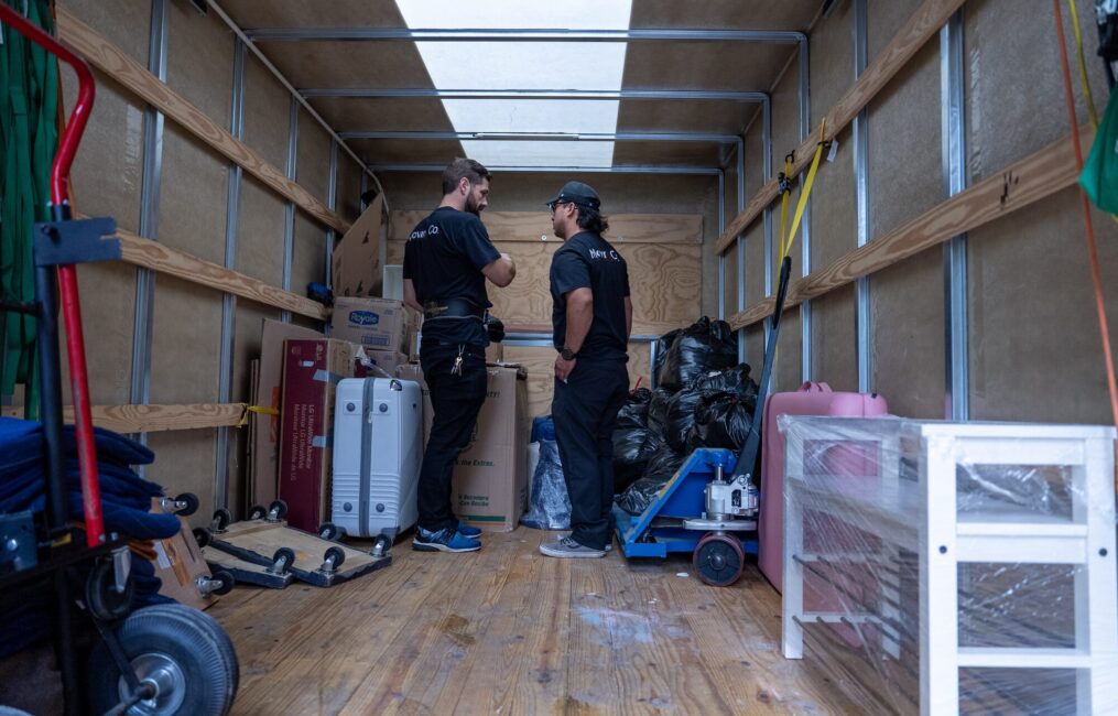 Two Moving Co. movers organizing furniture and boxes inside the truck