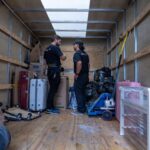 Two Moving Co. movers organizing furniture and boxes inside the truck