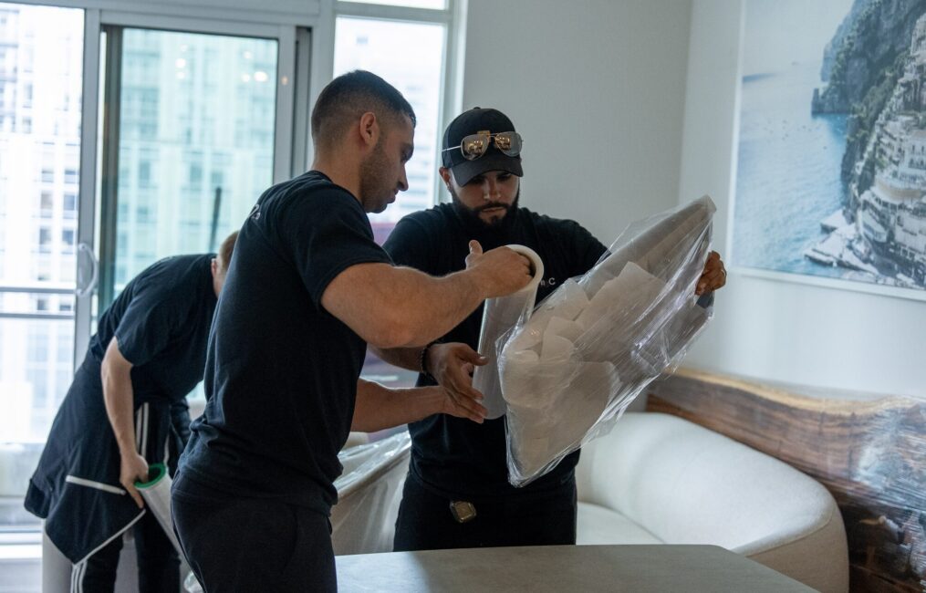 Three Moving Co. movers wrapping a chair in plastic