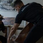 Two Moving Co. movers wrapping a chair with a metal base