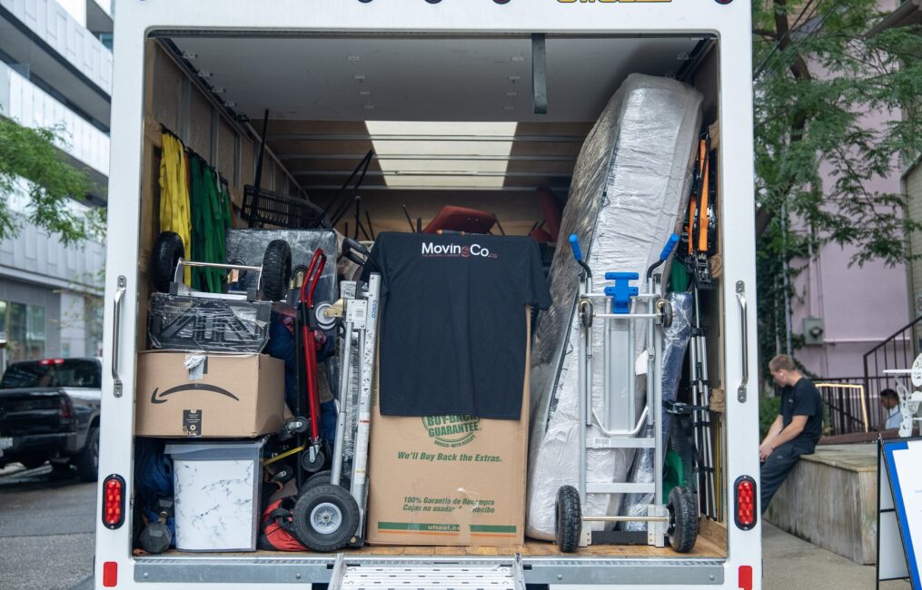 Back of the Moving Co. truck with the ramp down, packed with boxes and a mattress