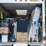 Back of the Moving Co. truck with the ramp down, packed with boxes and a mattress
