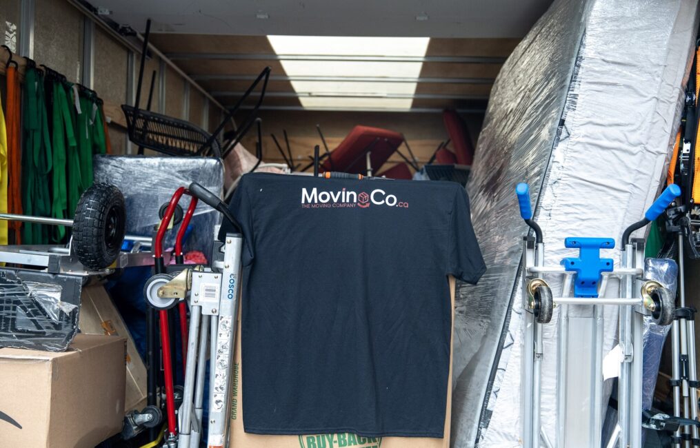 Inside the Moving Co. truck, with dollies, boxes and a Moving Co. shirt hanging up