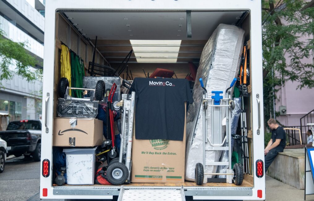 Moving Co. truck packed with boxes, a mattress and dollies, ramp down and ready to load