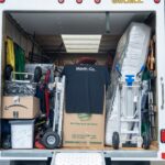 Moving Co. truck packed with boxes, a mattress and dollies, ramp down and ready to load